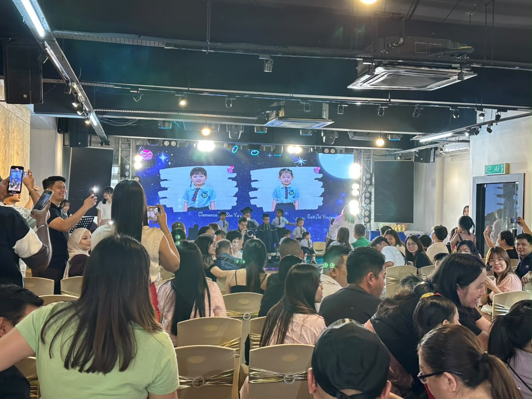 Graduation showcase with children on stage and a full audience of parents at Dreamlive Event Space Puchong