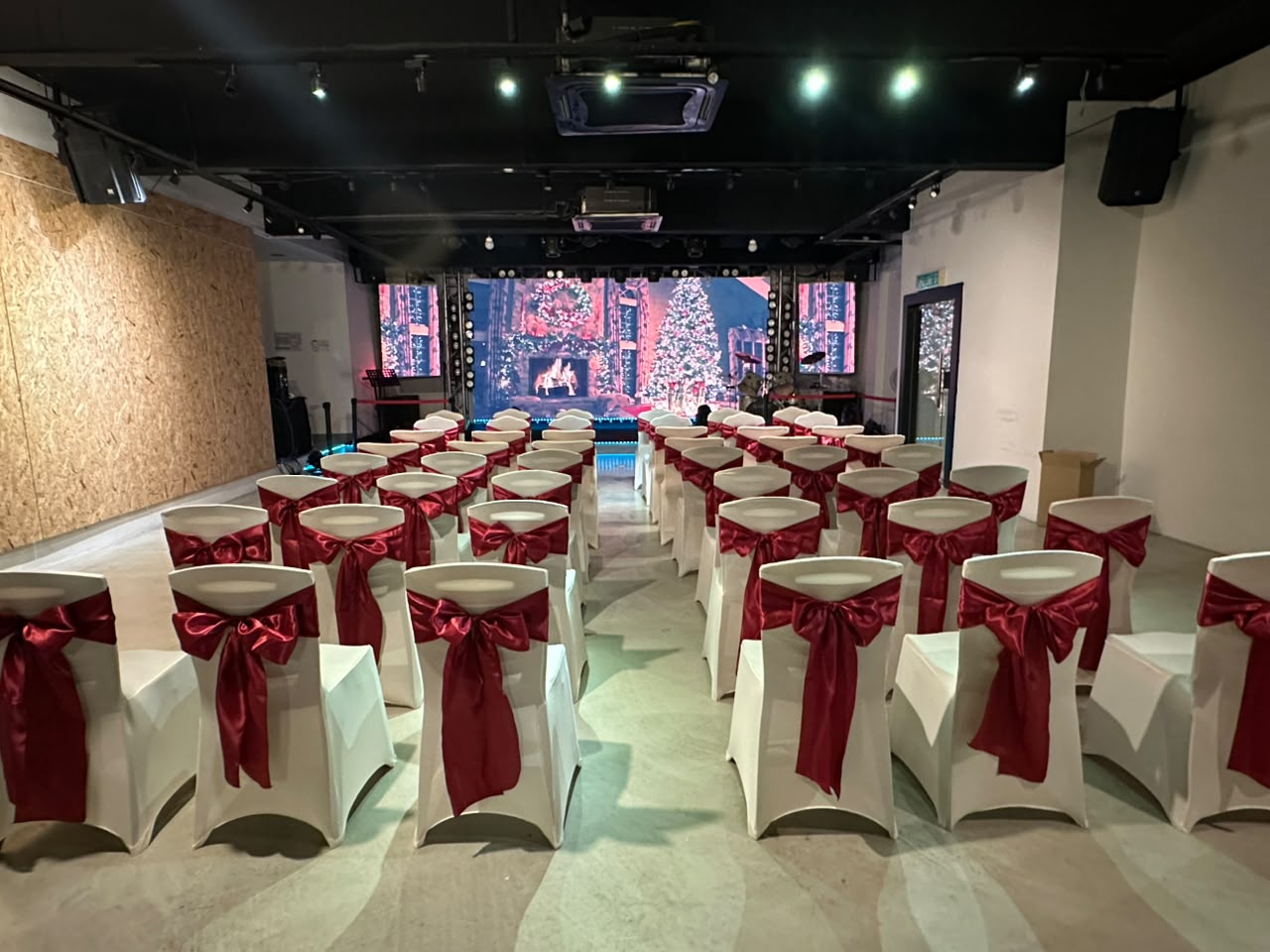 Theatre-style seating with white chairs and red ribbon bows facing the LED screen at Dreamlive Event Space